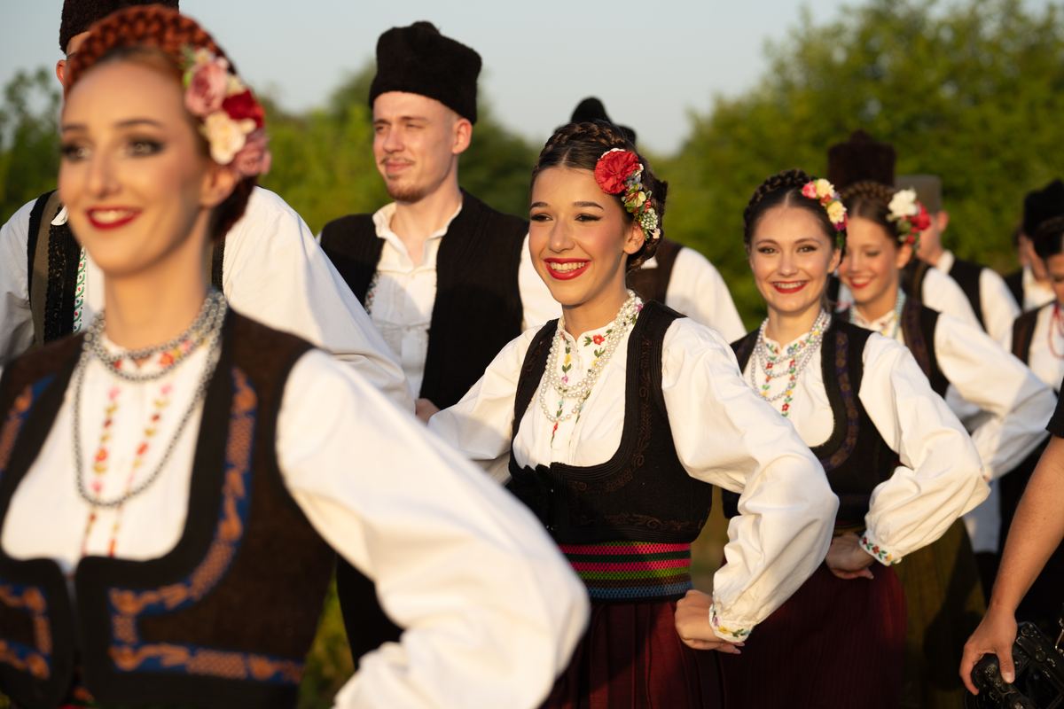 Nasmejani igrači u narodnoj nošnji na zalasku sunca u prirodi